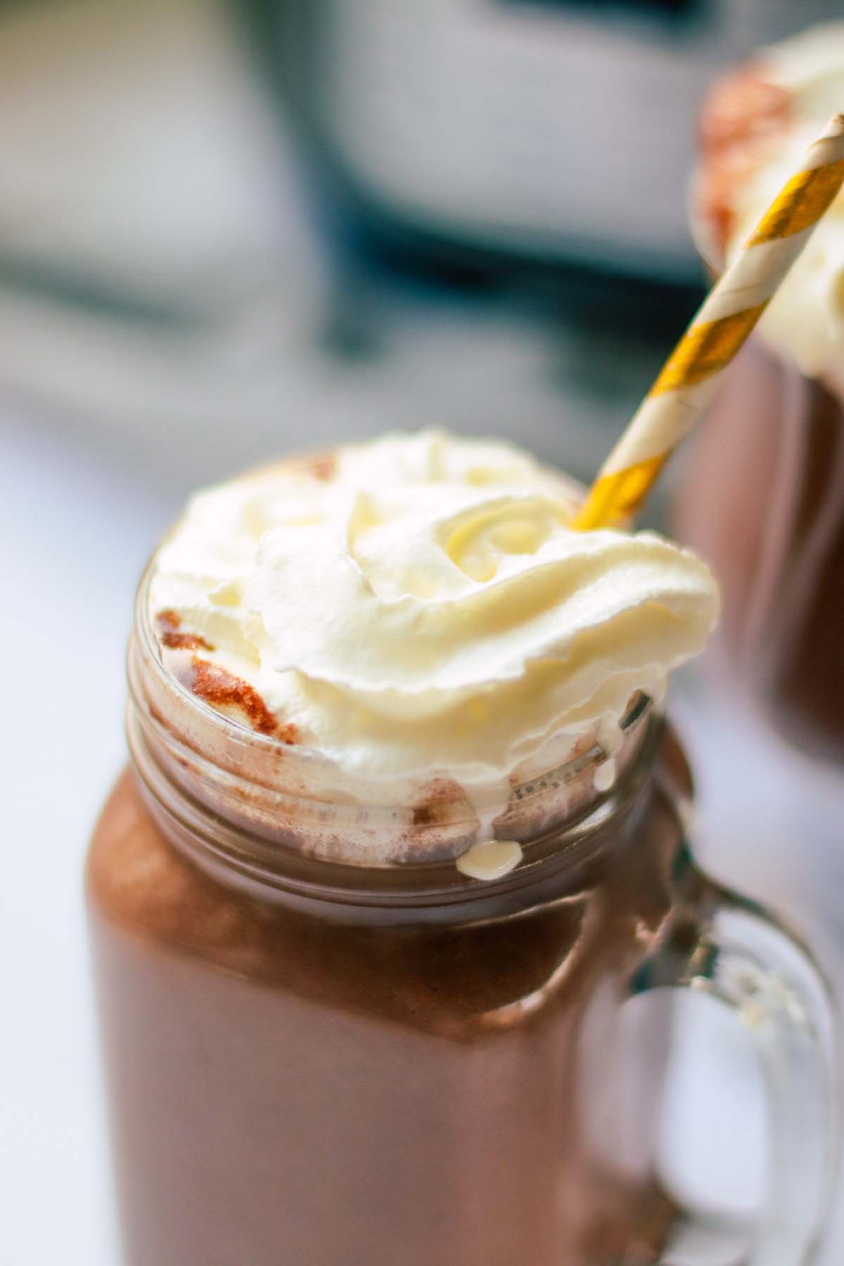 hot chocolate in a jar with whipped cream and a straw.