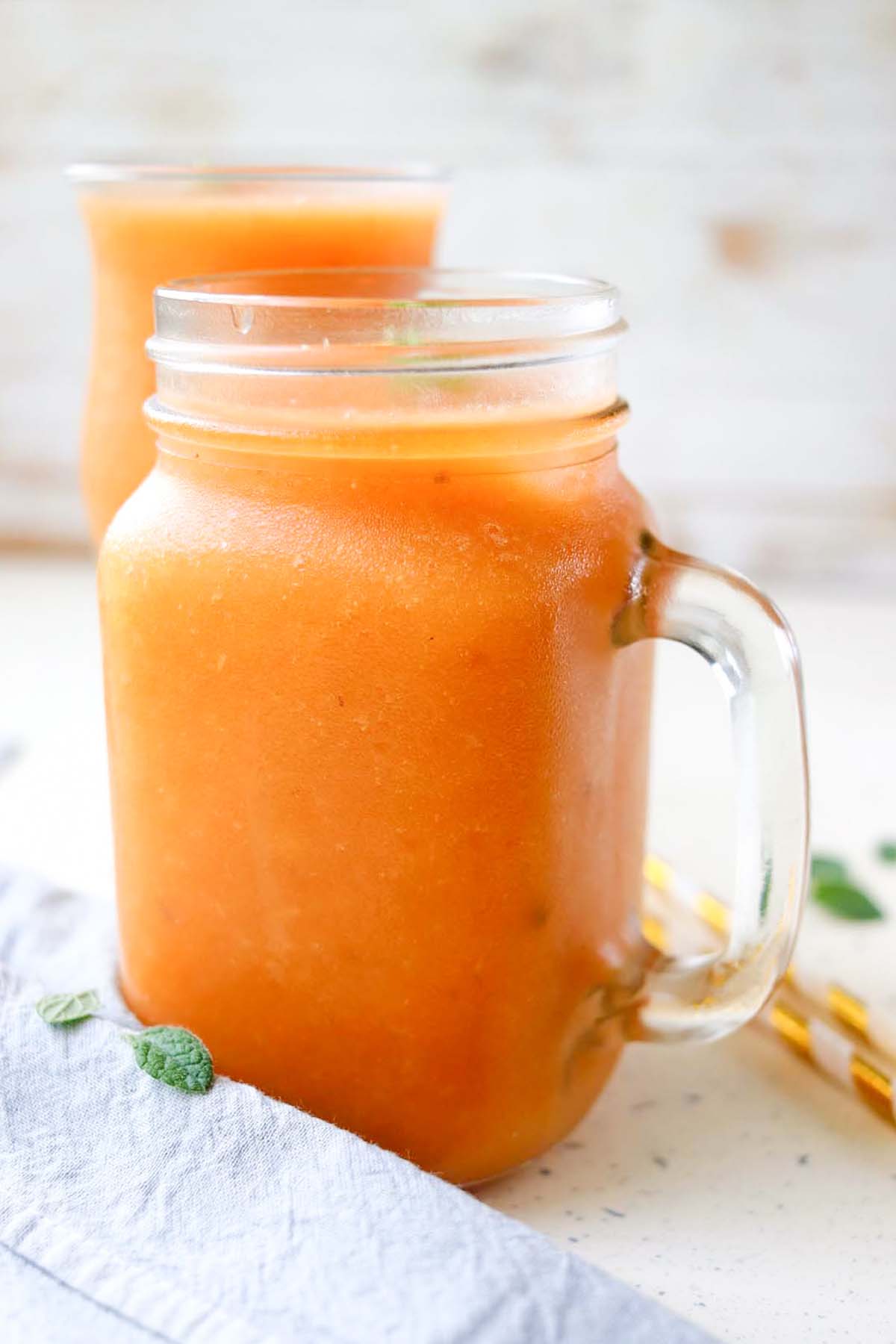 side view of orange smoothie in a jar.