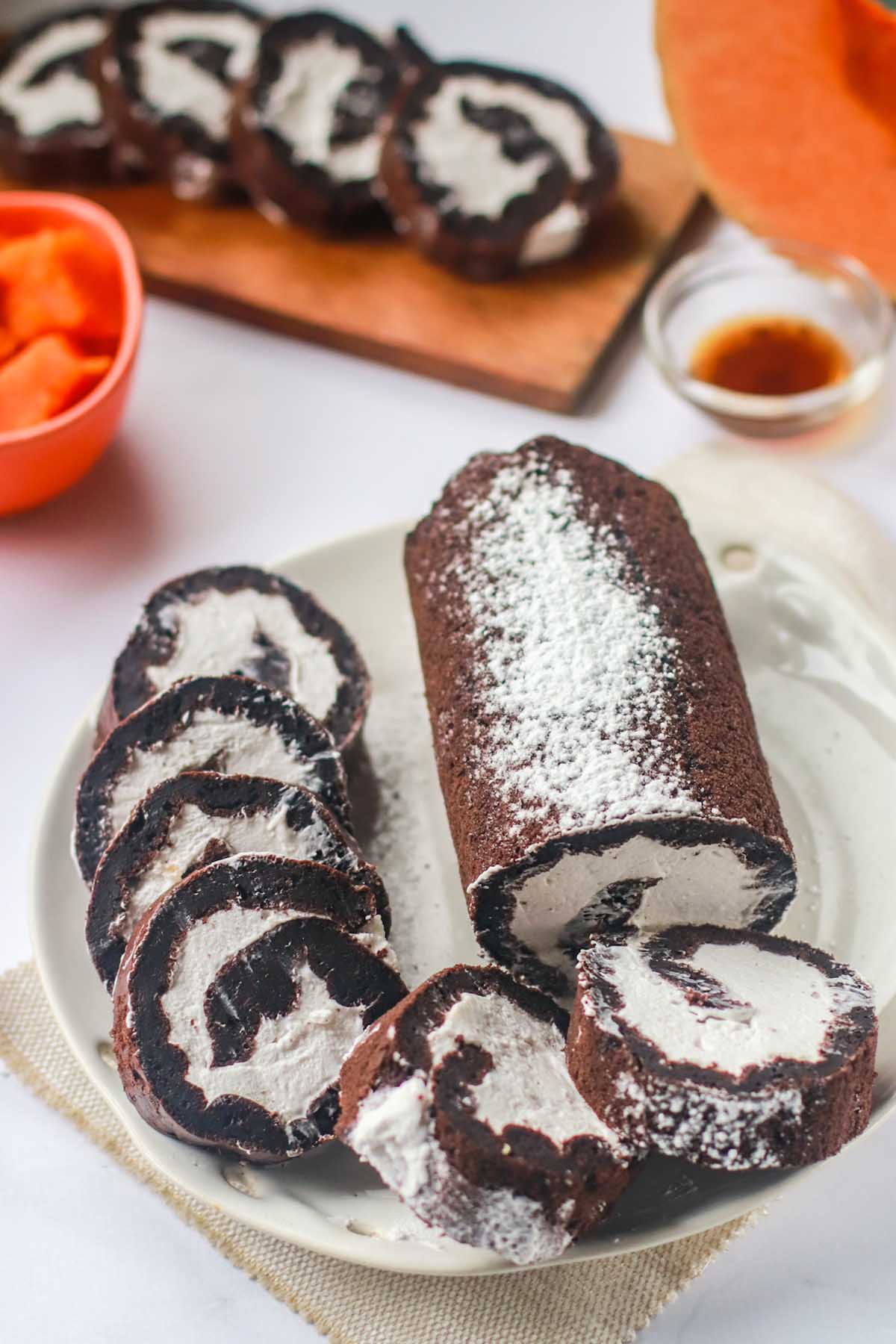 chocolate roll cake on a plate with slices.