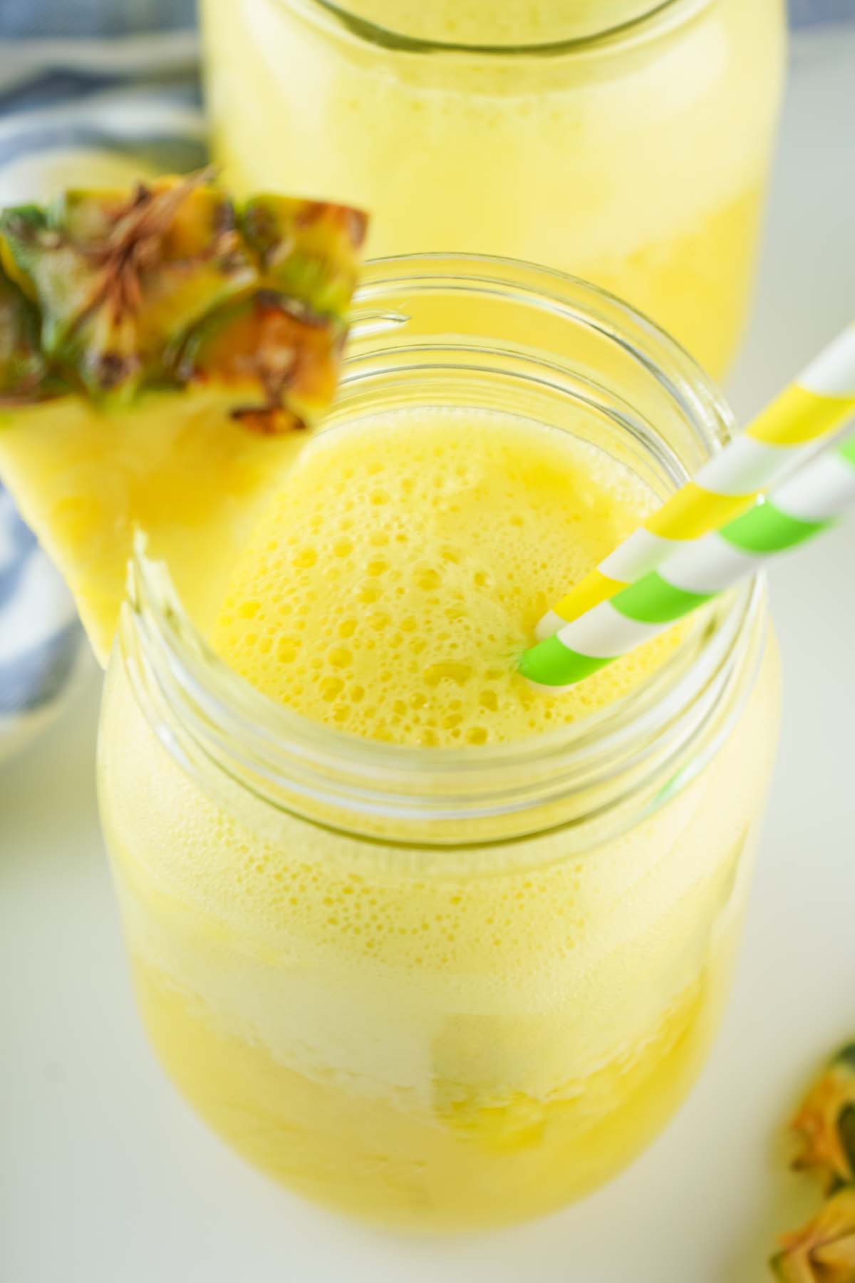 Top view of pineapple water in a glass with two straws.